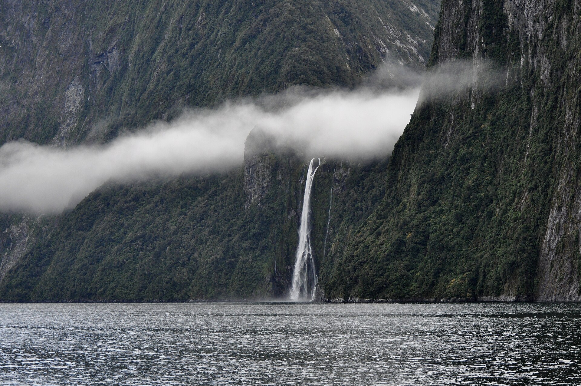 Mist drifting across the sheer cliffs and waterfall of Milford Sound